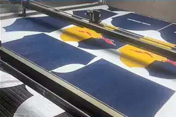 Our Factory Automated laser-guided cutting machine slicing multiple layers of fabric for custom sportswear production.